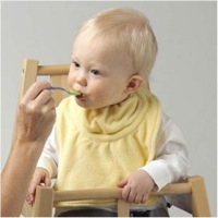 Koo-di Snugease Bib yellow on a baby in a highchair